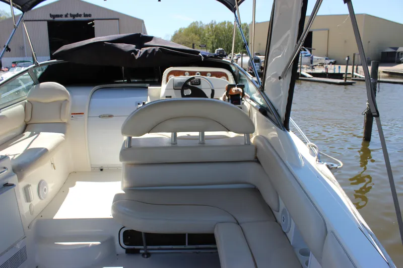 Slide: The Image of 2005 Larson Cabrio 310 boat interior with white seating, docked near a marina. - 10