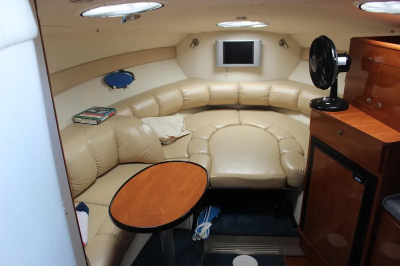 Slide: The Image of 2005 Larson Cabrio 310 cabin interior with leather seating, table, and small TV. - 17