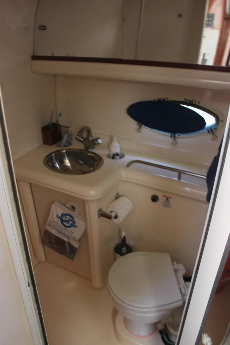 Slide: The Image of 2005 Larson Cabrio 310 boat bathroom with sink, toilet, and oval window. - 21