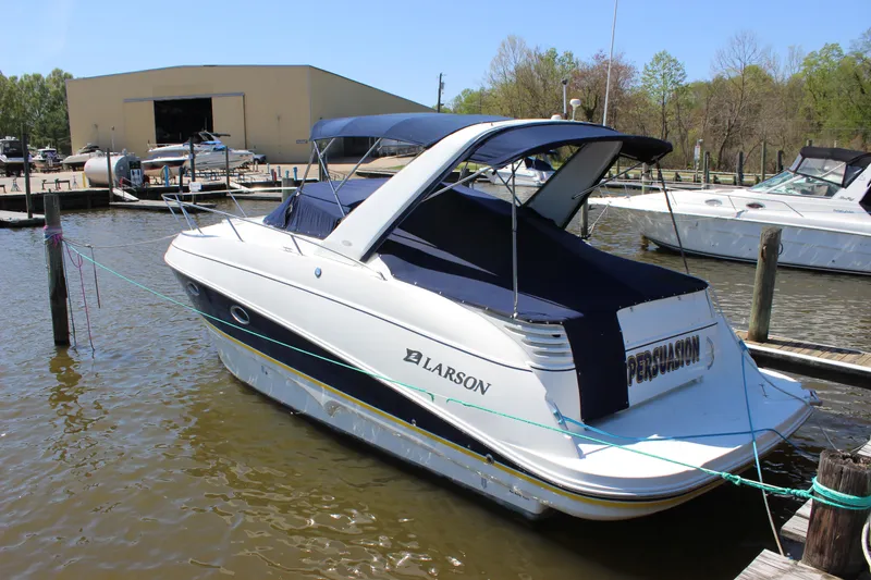 Slide: The Image of 2005 Larson Cabrio 310 boat docked at marina, featuring blue canopy and sleek design. - 4
