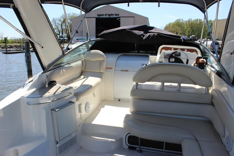 Slide: The Image of 2005 Larson Cabrio 310 boat interior with seating and helm, docked near a marina. - 7