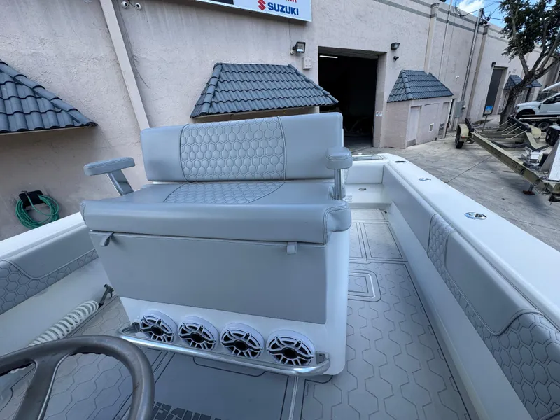 Slide: The Image of 2021 Contender 32ST boat interior with gray seating and speakers, docked near a building. - 15