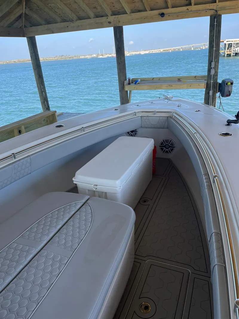 Slide: The Image of 2021 Contender 32ST boat docked under a wooden shelter with ocean view. - 2