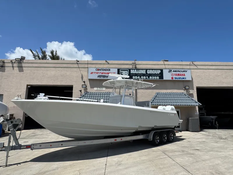 Slide: The Image of 2021 Contender 32ST boat on trailer outside marine shop under clear blue sky. - 6