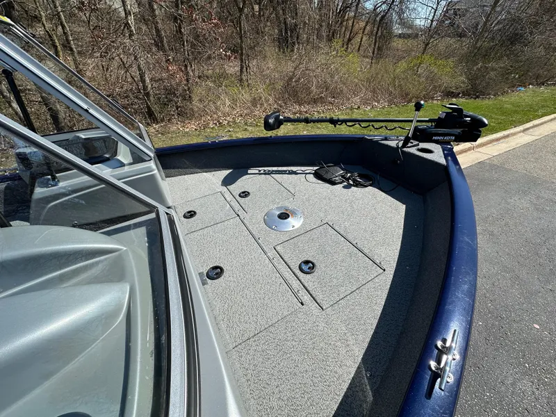 Slide: The Image of 2019 Tracker Pro Guide V-16 WT boat deck with trolling motor, parked near wooded area. - 6