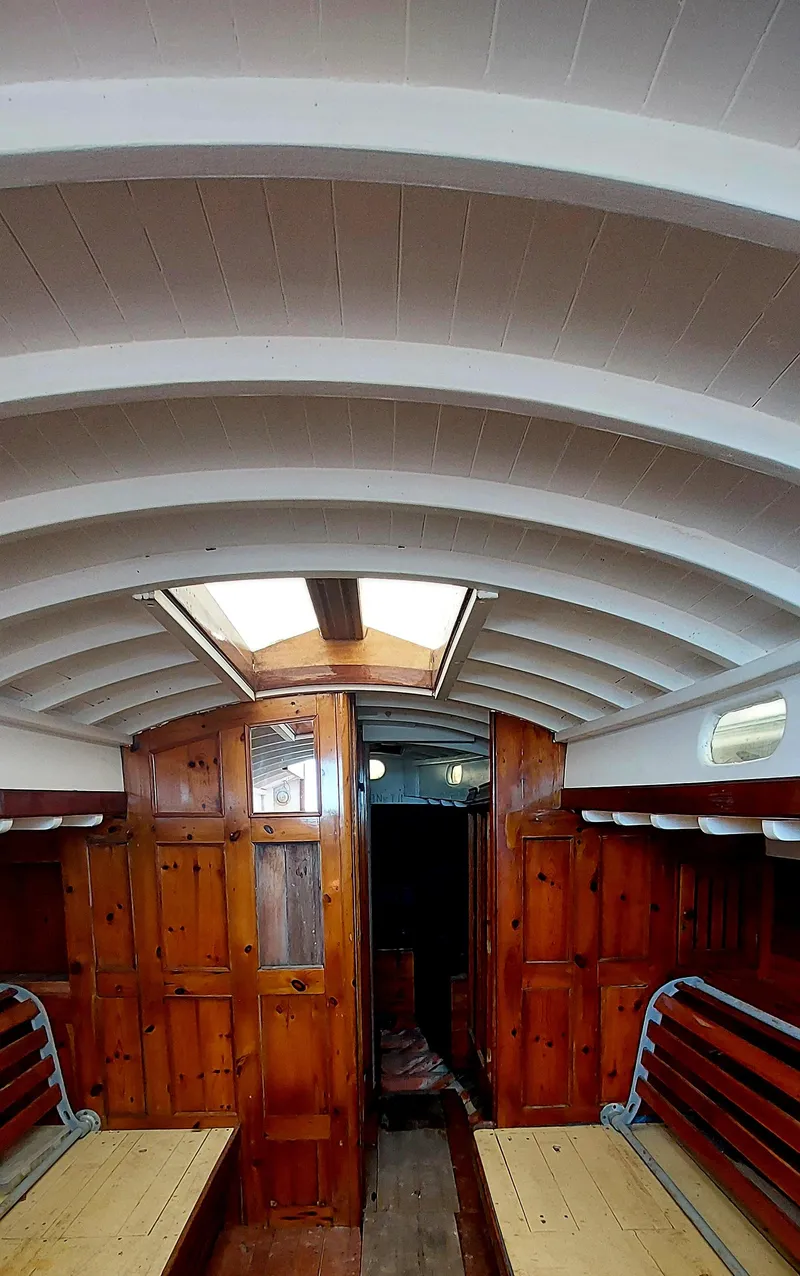 Slide: The Image of Interior of 1955 Concordia 41 Yawl, featuring wooden paneling and curved ceiling beams. - 2