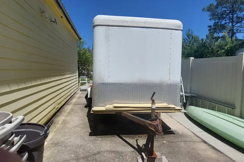 Slide: The Image of White trailer parked beside a yellow building, with a kayak nearby under a clear blue sky. - 22