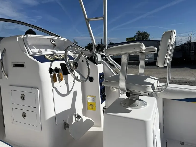 Slide: The Image of 2001 Pro-Line 27 Express boat helm with steering wheel and captain's chair under clear blue sky. - 15