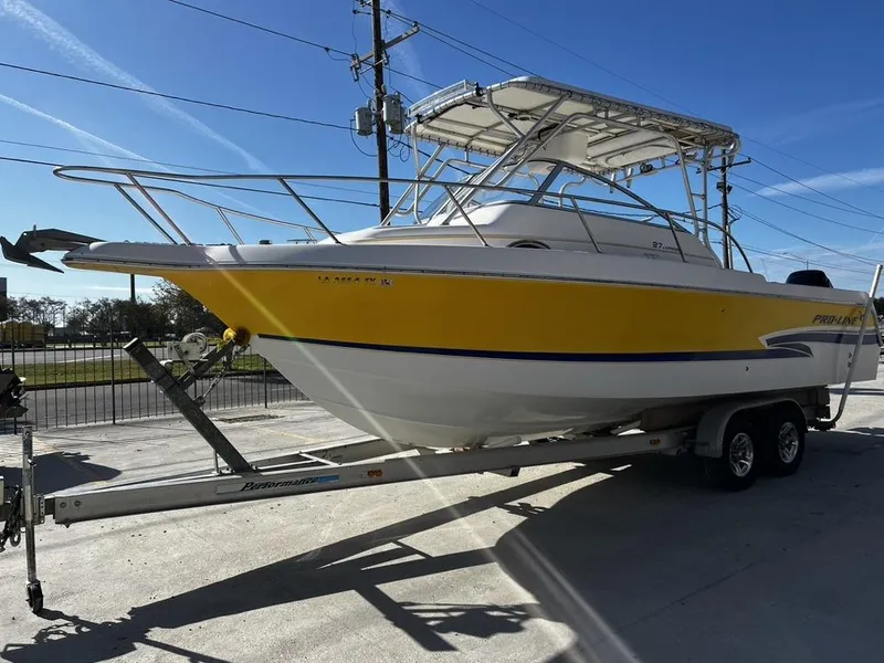 Slide: The Image of 2001 Pro-Line 27 Express boat on trailer, yellow and white, parked outdoors. - 5