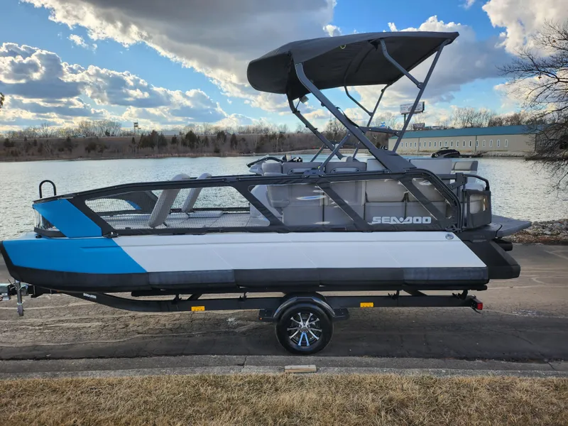 Slide: The Image of 2022 Sea-Doo Switch Sport 21 pontoon boat on trailer by a lake. - 8