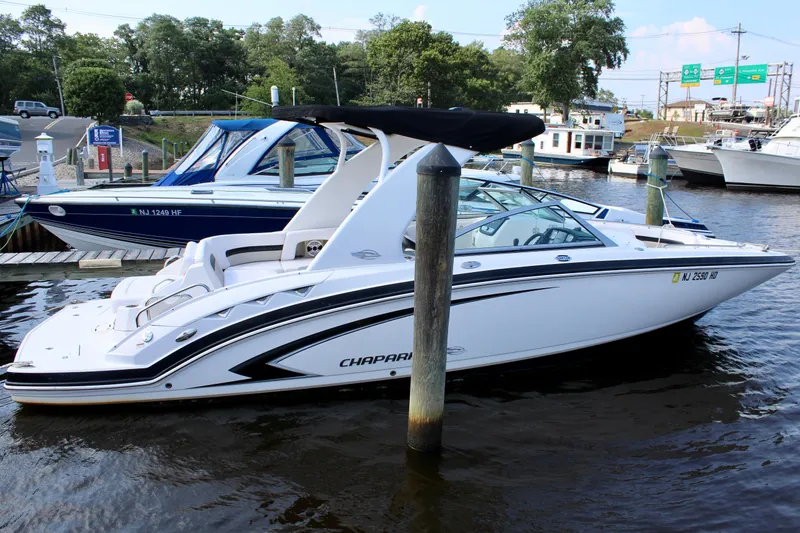 Slide: The Image of 2011 Chaparral 264 Sunesta boat docked in marina, featuring sleek white design and black canopy. - 10