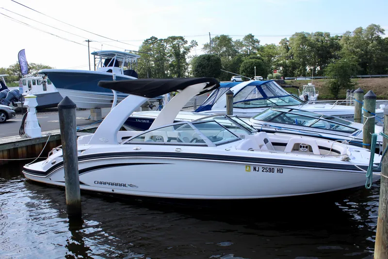 Slide: The Image of 2011 Chaparral 264 Sunesta boat docked at marina, featuring sleek design and white exterior. - 11