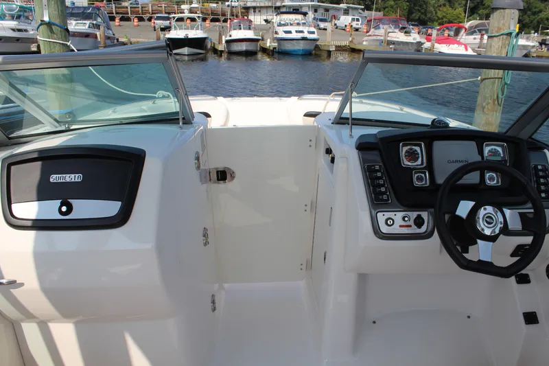 Slide: The Image of 2011 Chaparral 264 Sunesta boat dashboard with steering wheel, docked at marina. - 13