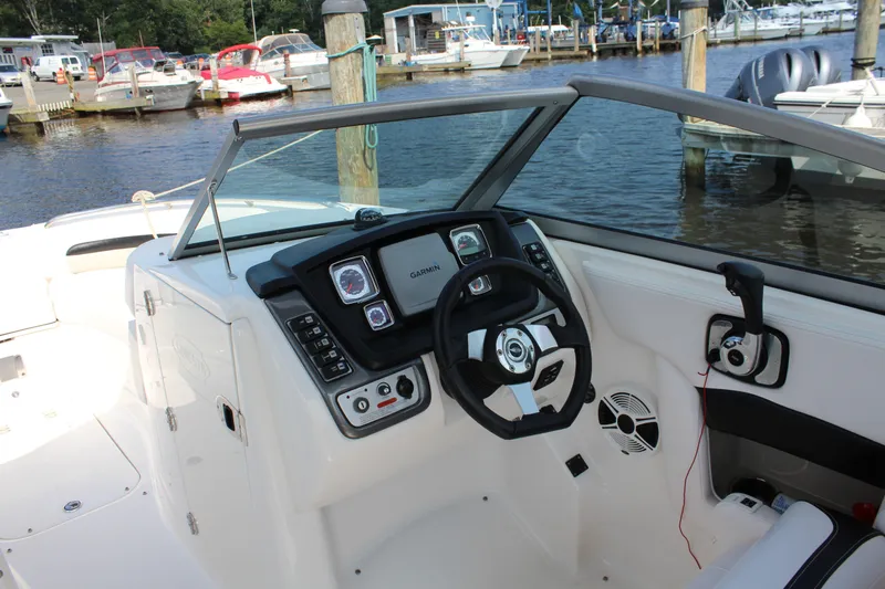 Slide: The Image of 2011 Chaparral 264 Sunesta boat dashboard with steering wheel, docked at marina. - 17