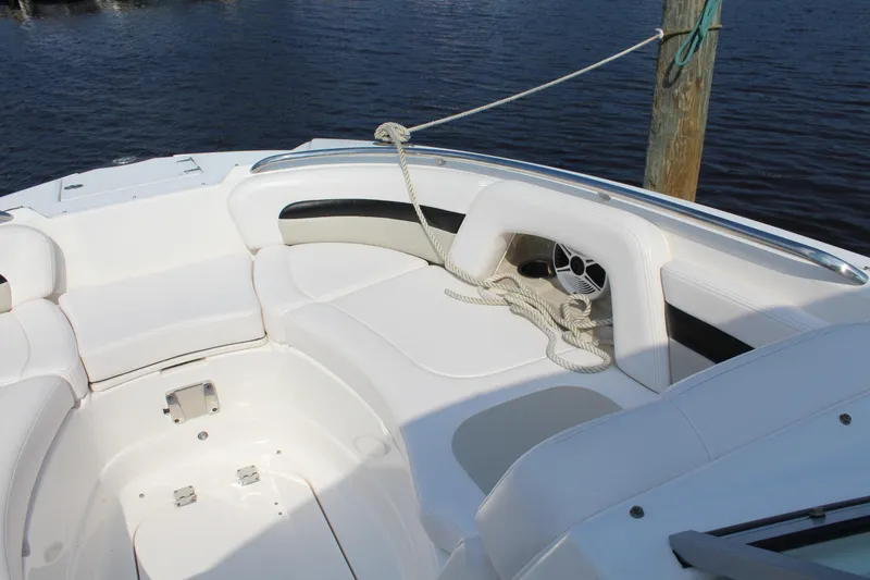 Slide: The Image of 2011 Chaparral 264 Sunesta boat interior with white seating and rope, docked by water. - 20