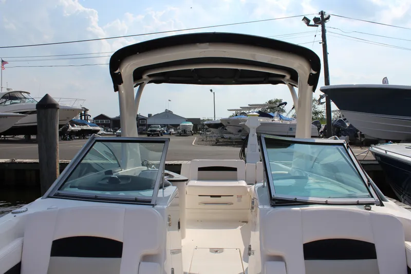 Slide: The Image of 2011 Chaparral 264 Sunesta boat with open deck and windshield, docked at a marina. - 21