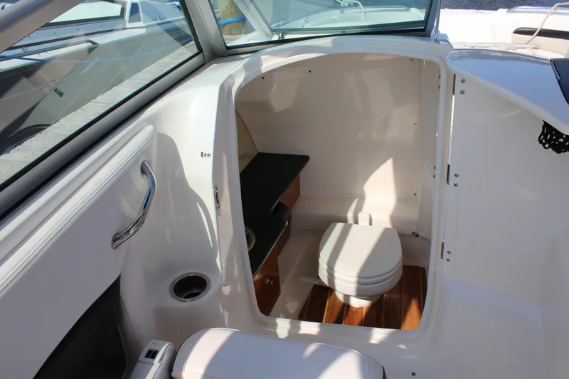 Slide: The Image of 2011 Chaparral 264 Sunesta boat interior with compact bathroom and seating area. - 29