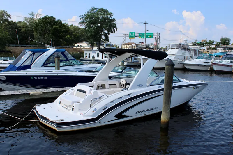Slide: The Image of 2011 Chaparral 264 Sunesta boat docked in a marina, surrounded by other vessels. - 9