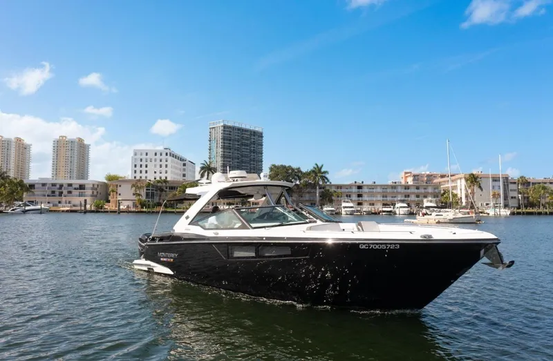 Slide: The Image of 2020 Monterey 385 Super Express boat cruising in a marina with cityscape background. - 11