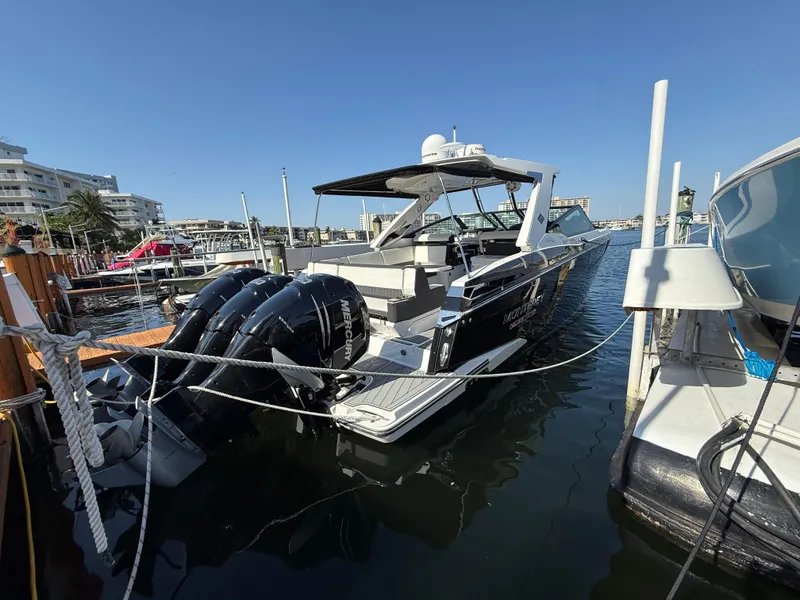 Slide: The Image of 2020 Monterey 385 Super Express boat docked in marina, featuring triple outboard engines. - 24