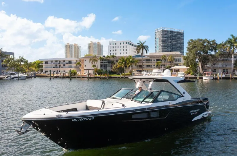 Slide: The Image of 2020 Monterey 385 Super Express boat cruising near waterfront buildings under a clear blue sky. - 6