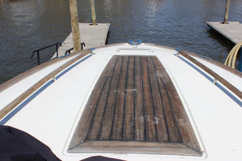 Slide: The Image of 2004 Chris-Craft Corsair 25 boat deck with wooden finish, docked by the water. - 10