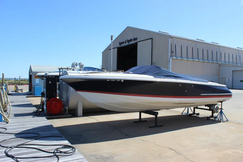 Slide: The Image of 2004 Chris-Craft Corsair 25 boat on a dock near a large storage building. - 2