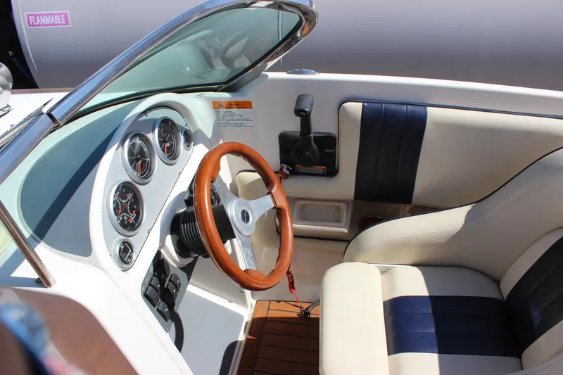 Slide: The Image of 2004 Chris-Craft Corsair 25 boat interior with wooden steering wheel and leather seating. - 20