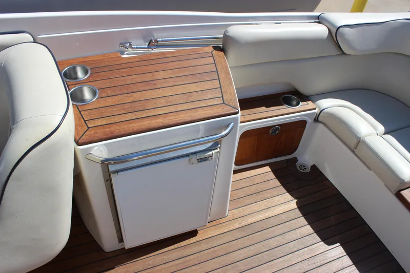 Slide: The Image of 2004 Chris-Craft Corsair 25 interior with wooden deck, cushioned seating, and built-in mini fridge. - 22