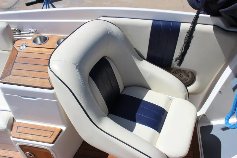 Slide: The Image of 2004 Chris-Craft Corsair 25 boat interior with cushioned seating and wooden accents. - 24