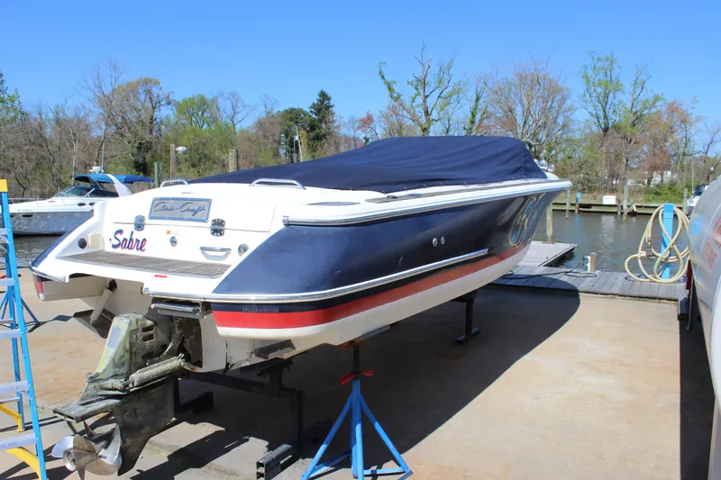 Slide: The Image of 2004 Chris-Craft Corsair 25 boat on dry dock, covered, with trees in the background. - 40