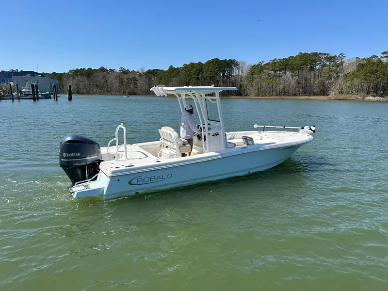 Slide: The Image of 2021 Robalo 246 Cayman boat cruising on a calm lake under clear blue skies. - 24
