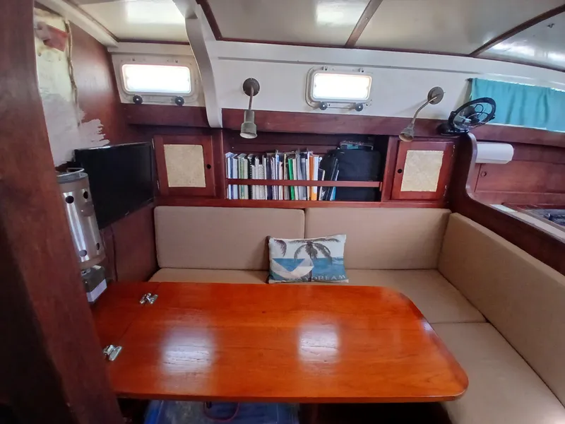Slide: The Image of Cozy 1977 Dickerson 41 sailboat interior with wooden table, bookshelves, and cushioned seating. - 14