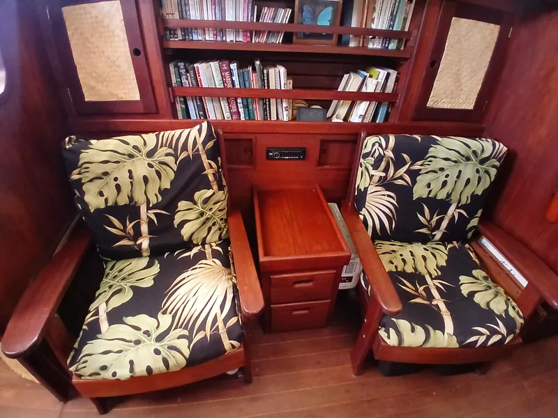 Slide: The Image of Cozy 1977 Dickerson 41 yacht interior with tropical-patterned chairs and bookshelf. - 17