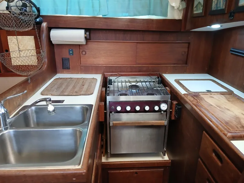 Slide: The Image of 1977 Dickerson 41 yacht kitchen with stainless steel sink, stove, and wooden cabinetry. - 18