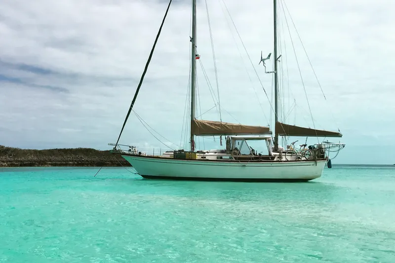 Slide: The Image of Sailboat Dickerson 41 (1977) anchored in clear turquoise waters under a cloudy sky. - 3