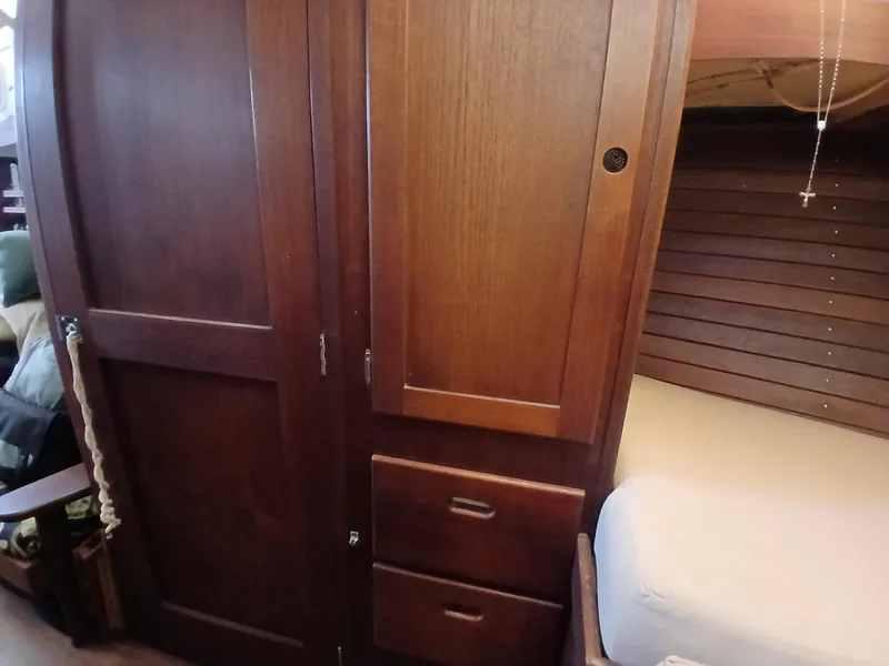 Slide: The Image of Wooden interior of a 1977 Dickerson 41 sailboat, featuring cabinets and a cozy sleeping area. - 31