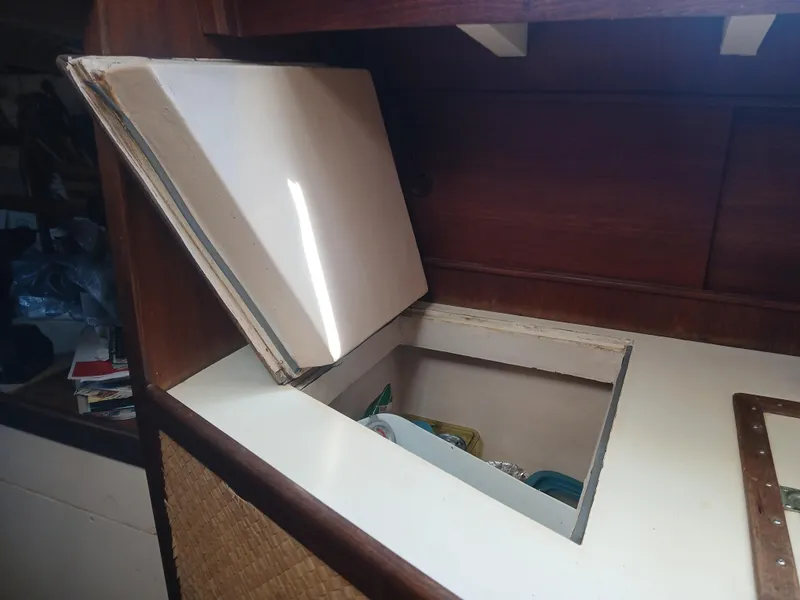 Slide: The Image of Storage compartment in a 1977 Dickerson 41 boat, featuring a hinged lid and wooden interior. - 34