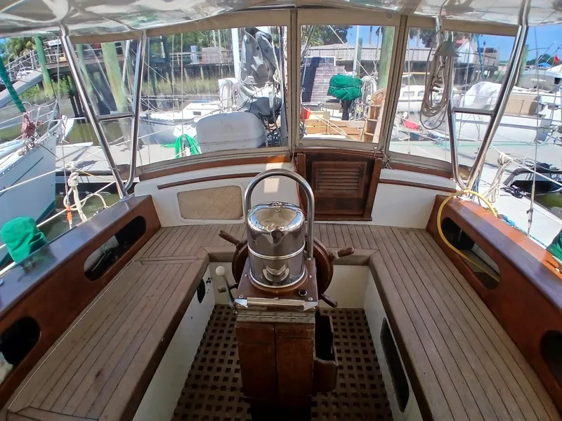 Slide: The Image of 1977 Dickerson 41 sailboat cockpit with wooden benches and steering wheel, docked at a marina. - 35