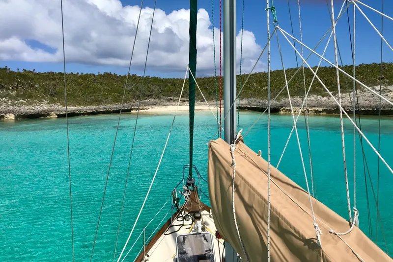 Slide: The Image of Sailboat Dickerson 41 (1977) on turquoise waters near a sandy beach and lush greenery. - 4