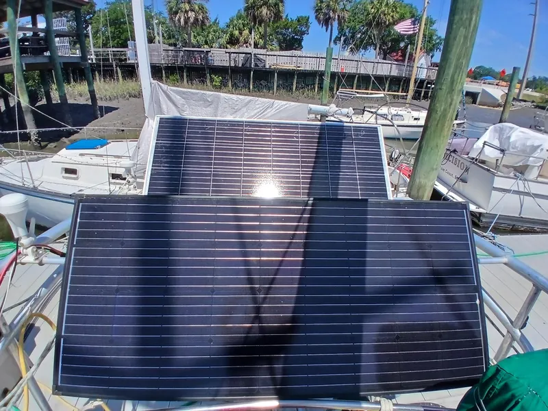Slide: The Image of Solar panels on a 1977 Dickerson 41 sailboat deck, docked near a wooden pier. - 47