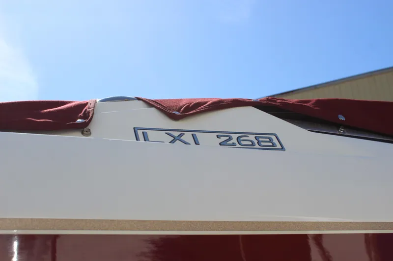 Slide: The Image of 2005 Larson LXi 268 boat with maroon cover under clear blue sky. - 19