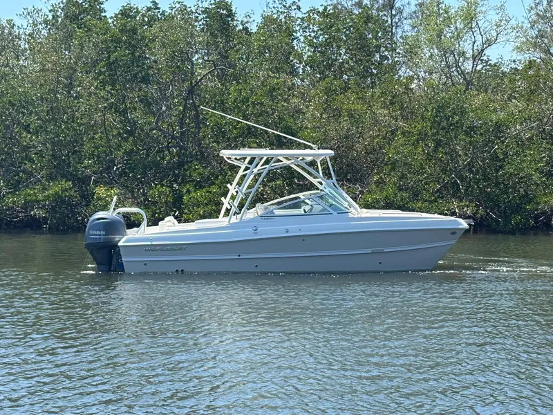 The Image of 2025 World Cat 230 SD boat on calm water, surrounded by lush greenery. - 0