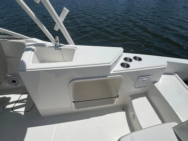 Slide: The Image of 2025 World Cat 230 SD boat interior with sink and cup holders, on calm water. - 10