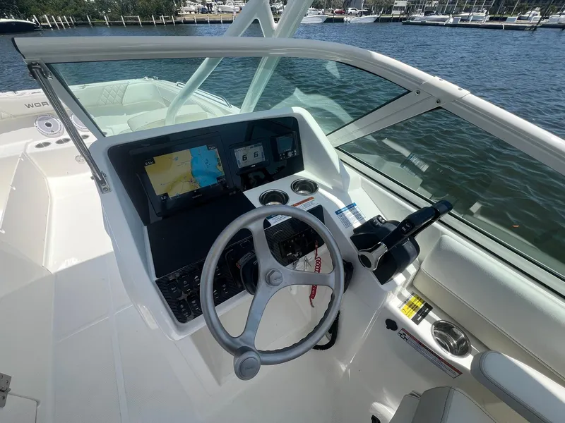 Slide: The Image of 2025 World Cat 230 SD boat cockpit with steering wheel and navigation system, docked by the water. - 20