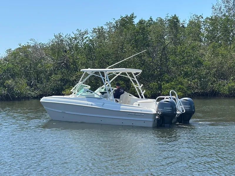 Slide: The Image of 2025 World Cat 230 SD boat cruising on a calm river with lush greenery. - 5