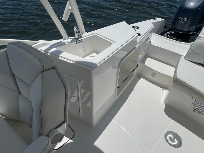 Slide: The Image of 2025 World Cat 230 SD boat interior with seating and sink, on calm water. - 9