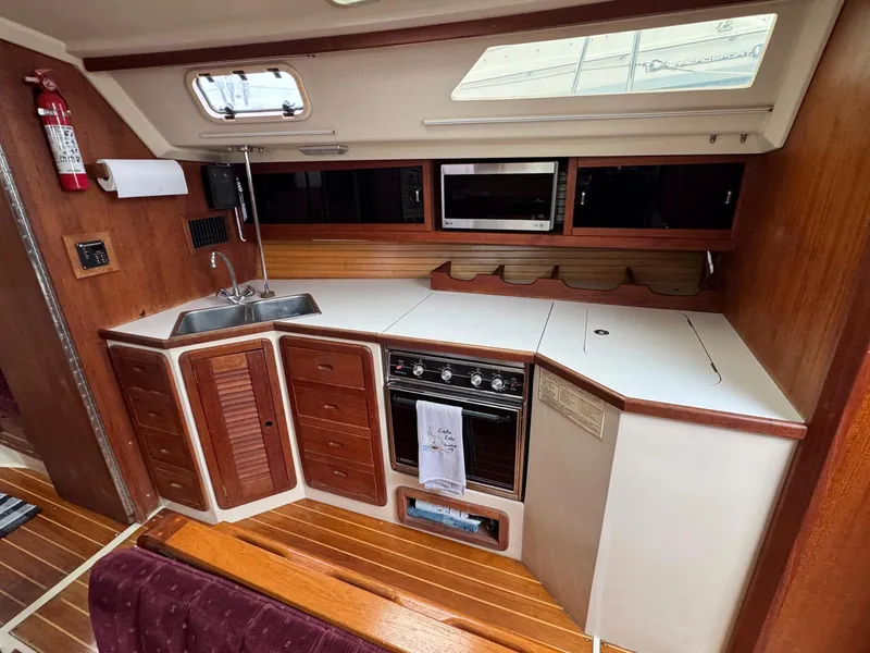 Slide: The Image of 1989 Catalina 42 MkII yacht kitchen with stove, sink, and wooden cabinetry. - 18