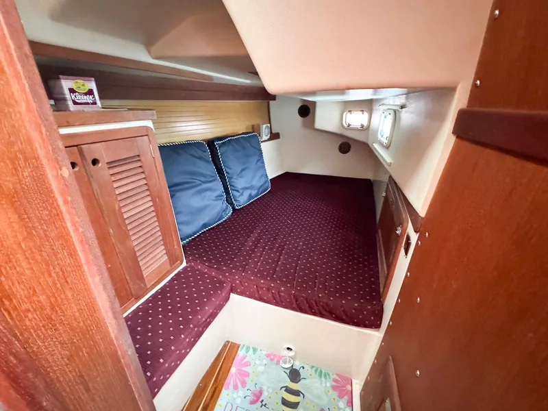 Slide: The Image of Cozy cabin interior of a 1989 Catalina 42 MkII sailboat with red bedding and wooden accents. - 22