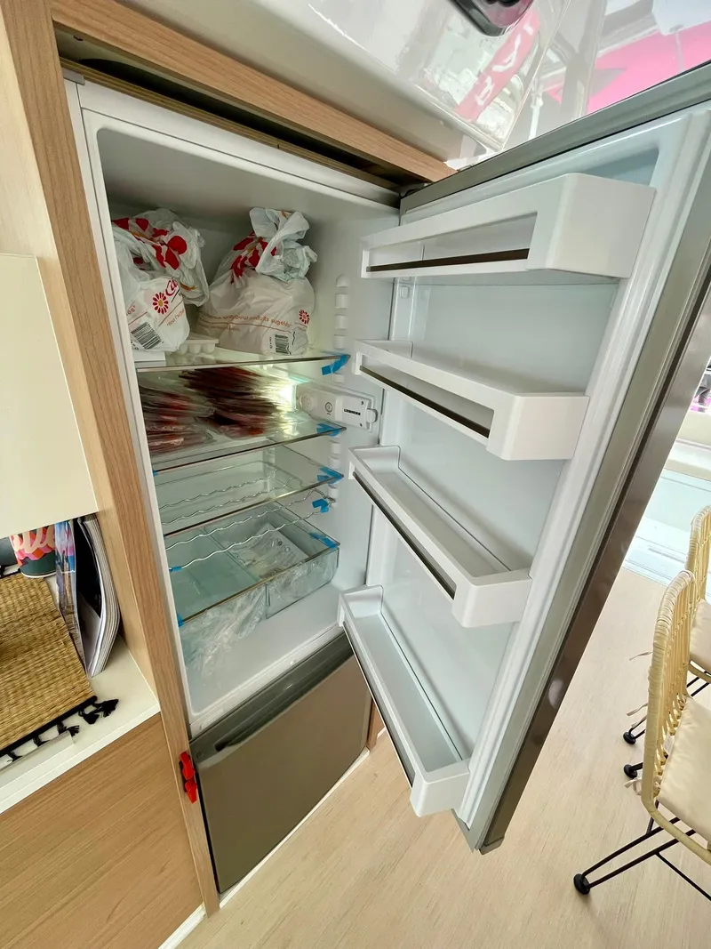 Slide: The Image of Open refrigerator in a 2026 Bali CATSPACE, showing organized shelves and food items. - 10